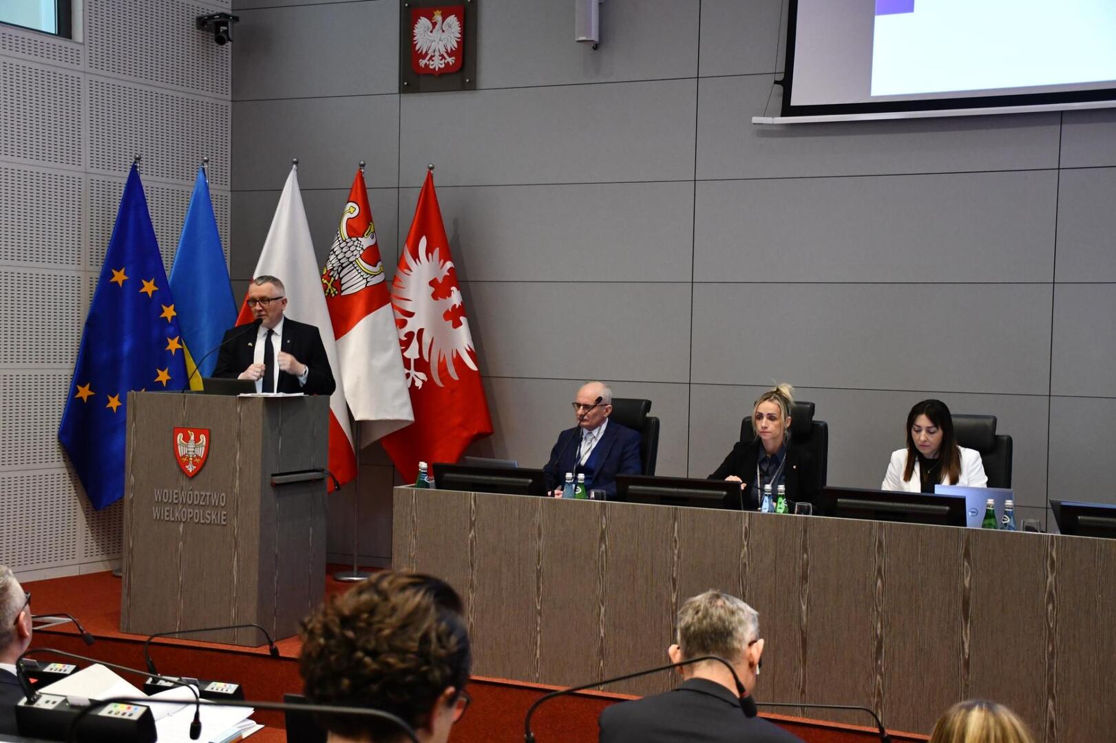 sala wykładowa. przy mównicy straszy mężczyzna.